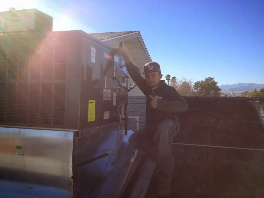HVAC technician performing AC Tune-Up on a rooftop unit in Norton