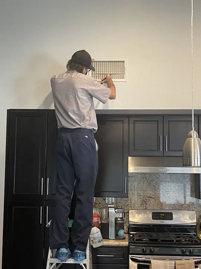 Technician inspecting an air vent during HVAC service in Norton